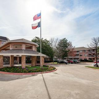 A building with flags flying above a parking lot on a clear day.
