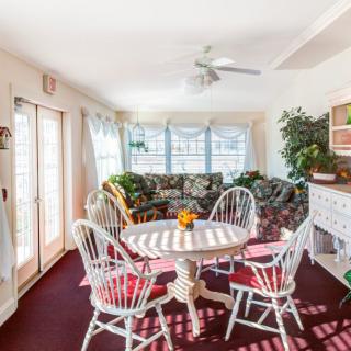A bright and cozy dining area with a round table, surrounded by chairs and large windows.