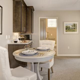 A cozy dining area with a round table set for two, adjacent to a modern kitchen.