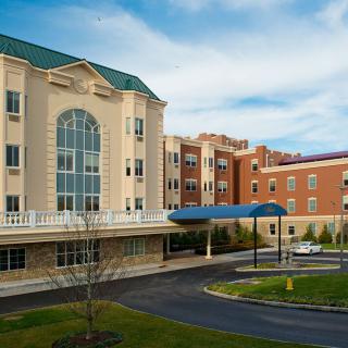 A modern hospital building with a well-maintained exterior and landscaping under a clear blue sky.