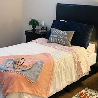 A cozy and inviting bedroom setup featuring a neatly made bed with decorative pillows and a warm blanket.