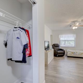 A view from the closet into a cozy living room with a sofa, recliner, and a television.