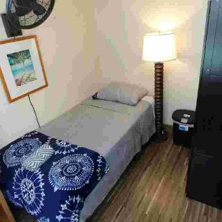 A cozy, minimalist bedroom with a single bed and a standing lamp.