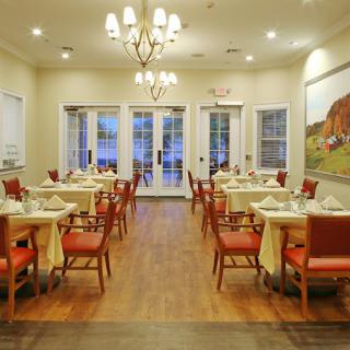 A beautifully set dining room with elegant lighting and neatly arranged tables and chairs.