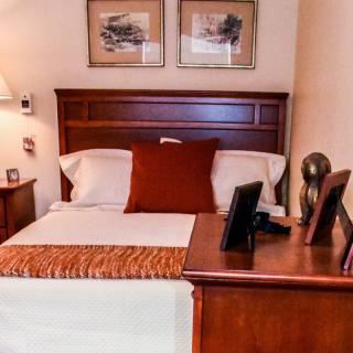 Cozy bedroom with a neatly made bed, nightstand, and decorative artwork.