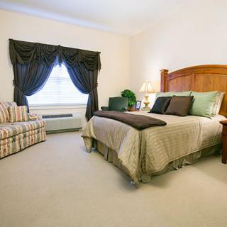 A cozy bedroom with a bed, nightstands, and curtains.