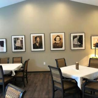A cozy dining area featuring tables and chairs, adorned with framed photographs on the wall.