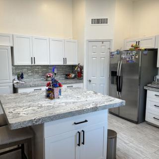 A modern kitchen featuring white cabinets, a central island, and stainless steel appliances.