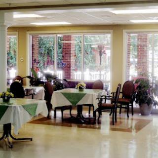 A cozy dining area featuring neatly arranged tables and chairs, enhanced by natural light and decorative plants.
