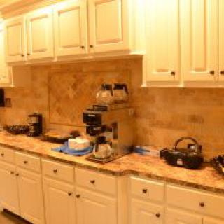 A kitchen counter with various appliances and white cabinets.