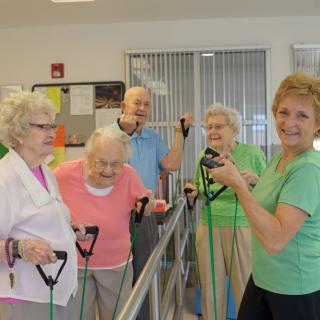 A group of seniors engaging in an indoor exercise session using resistance bands.