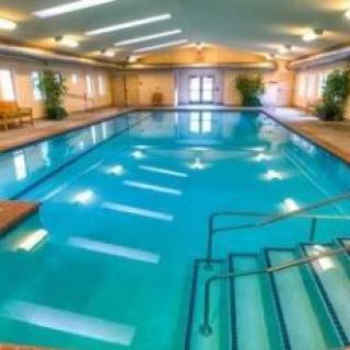 An inviting indoor swimming pool with clear blue water and ample lighting.
