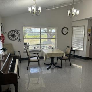 A bright and spacious dining area featuring a piano, a table with chairs, and large windows that provide a view of the outdoors.