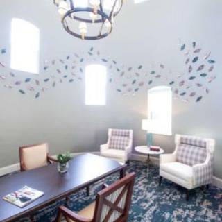 A modern living room with stylish decor, featuring a table, comfortable chairs, and artistic wall designs.