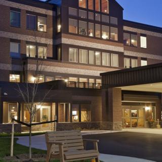 A well-lit building exterior in the evening with large windows and a welcoming entrance.