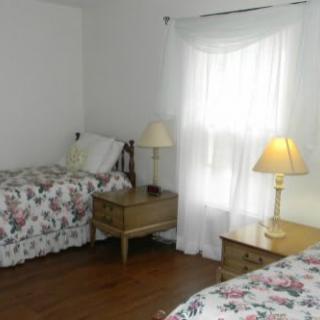 A cozy bedroom with twin beds adorned in floral bedding, illuminated by warm table lamps.