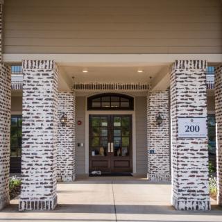 The entrance of a building with brick columns and a glass door.