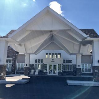 A modern building entrance with a prominent triangular roof design under a clear sky.