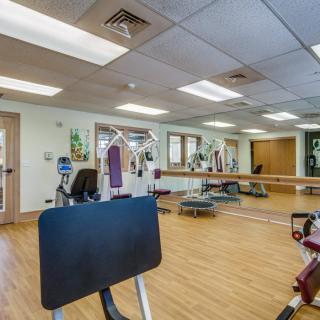 A gym with various exercise equipment and mirrors on the walls.