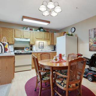 A cozy kitchen and dining area featuring wooden cabinets, a round table with chairs, and various appliances.