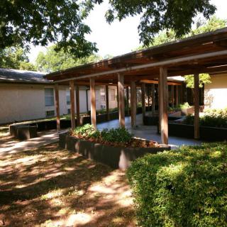 A peaceful outdoor area with a wooden pergola and manicured garden.