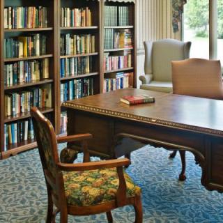 A cozy library corner with a wooden desk and bookshelves filled with books.