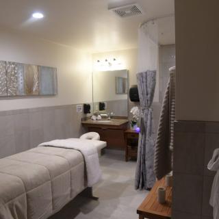 A serene massage room with a single bed, soft lighting, and calming decor.