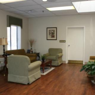 A cozy waiting room with chairs, a small table, and decorative plants.