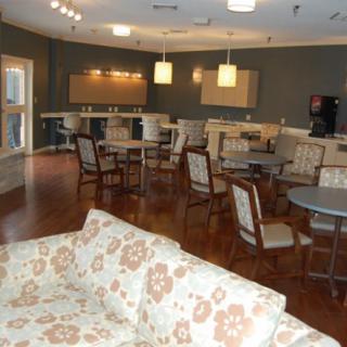 A modern cafe interior with tables and chairs, featuring soft lighting and a relaxed lounge atmosphere.