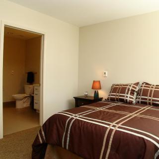 A cozy bedroom with a neatly made bed and an adjacent bathroom.