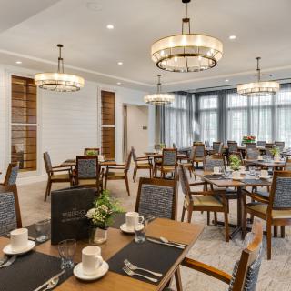 An elegant dining room with neatly arranged tables and chairs, complete with chandeliers and formal table settings.