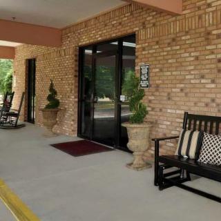 Entrance with glass doors and a welcoming seating area featuring benches and potted plants.