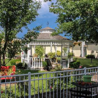 A picturesque garden with a white gazebo surrounded by lush greenery and outdoor seating.