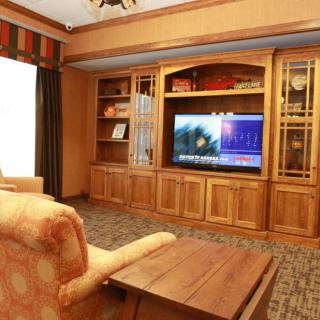 Cozy living room with a large television and wooden shelving.