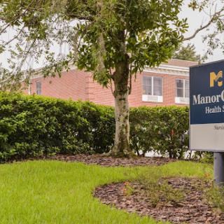A sign for a facility, surrounded by lush greenery and well-maintained landscaping.