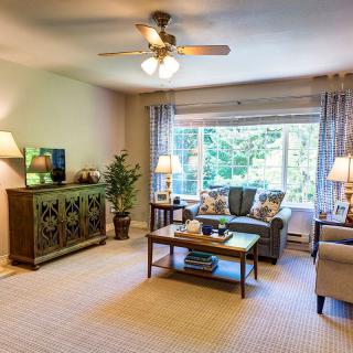 A cozy living room with a sofa, coffee table, and large window offering natural light.