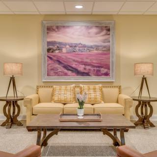 A cozy living room with a sofa, framed artwork, and matching lamps on either side.