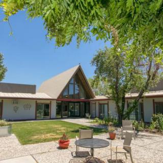 A modern house with a triangular roof surrounded by a spacious backyard and patio area.