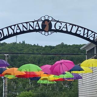 Colorful umbrellas hang beneath the gateway arch labeled 'POLLYANNA GATEWAY'.