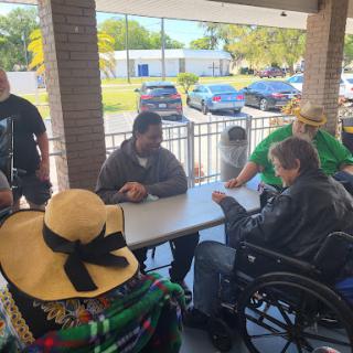A group of people enjoying a social gathering outdoors, seated around a table.