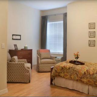 A cozy bedroom with a bed, chairs, and a window with curtains.