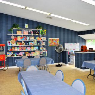 A colorful classroom featuring art supplies and bookshelves against blue walls.