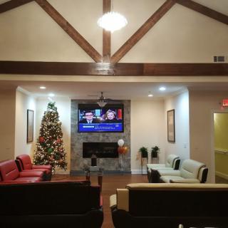 A cozy living room decorated for the holidays with a Christmas tree and a television above the fireplace.