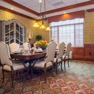 A traditional dining room with an elegant table set, chandelier, and ornate furnishings.