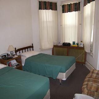A hotel room with two twin beds and large windows.