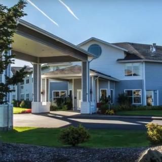 A large residential building with a covered entrance and landscaped surroundings.