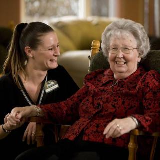 An elderly woman and her caregiver share a joyful moment together.