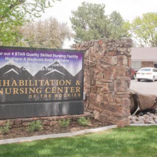 An outdoor sign for a rehabilitation and nursing center at the entrance of the building.
