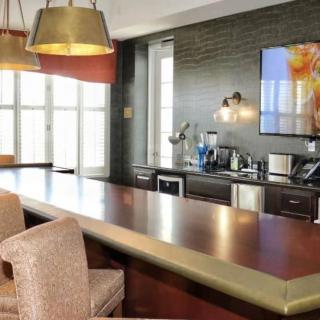 A modern kitchen interior featuring a sleek countertop, bar stools, and contemporary lighting.