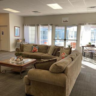 A cozy living room with comfortable couches and a coffee table, sunlit through large windows.